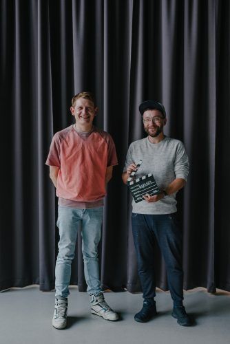 Zdjęcie, Adam Kruk i Lech Moliński pozują obok siebie na tle zasłony z klapsem filmowym w ręce